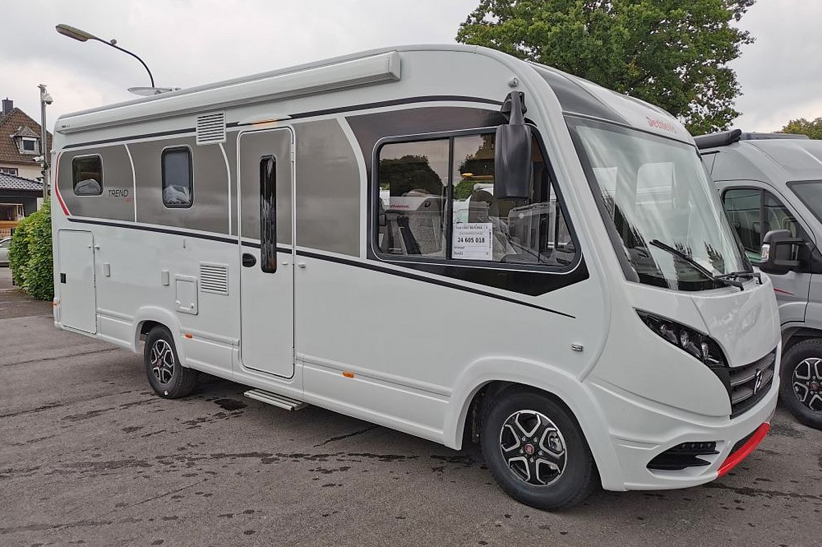 Ein weißes vollintegriertes Wohnmobil mit einem grauen waagerechten Streifen an der Seite.