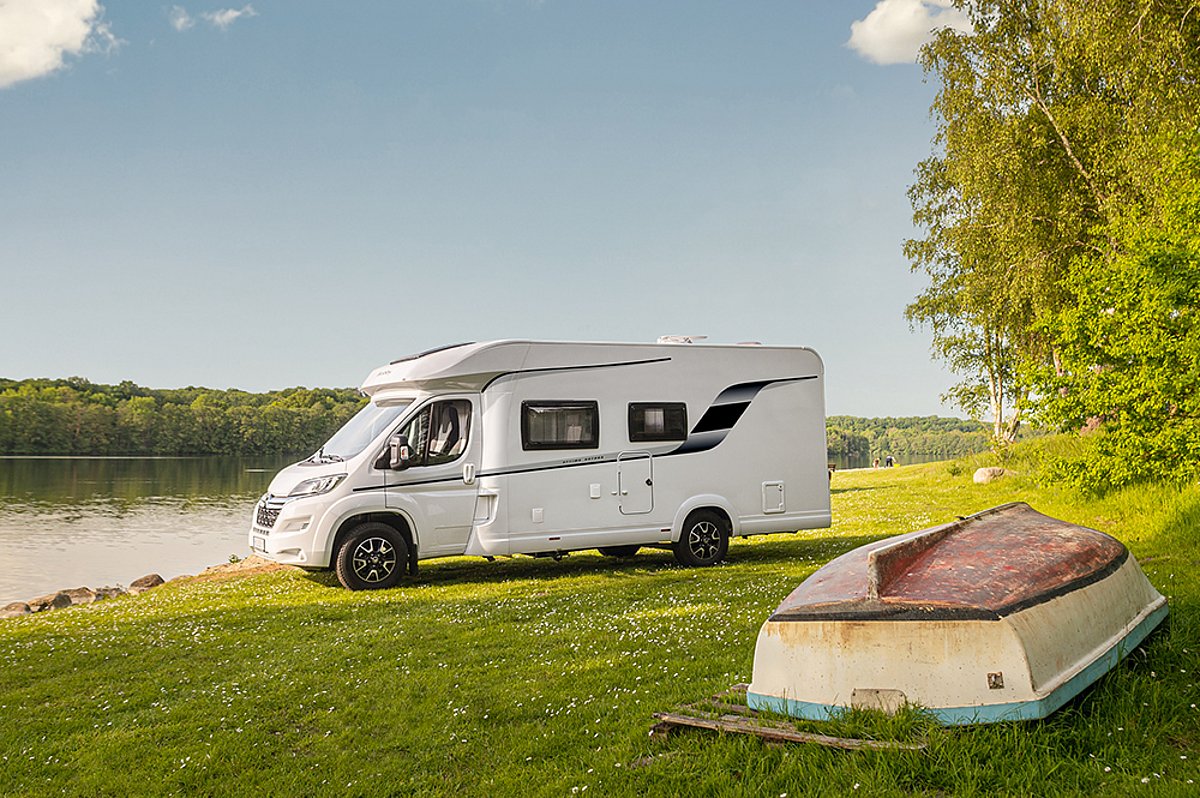 Ein Wohnmobil der Marke Sunlight steht auf einer Wiese. Im Vordergrund ist ein umgedrehtes Boot zu sehen.